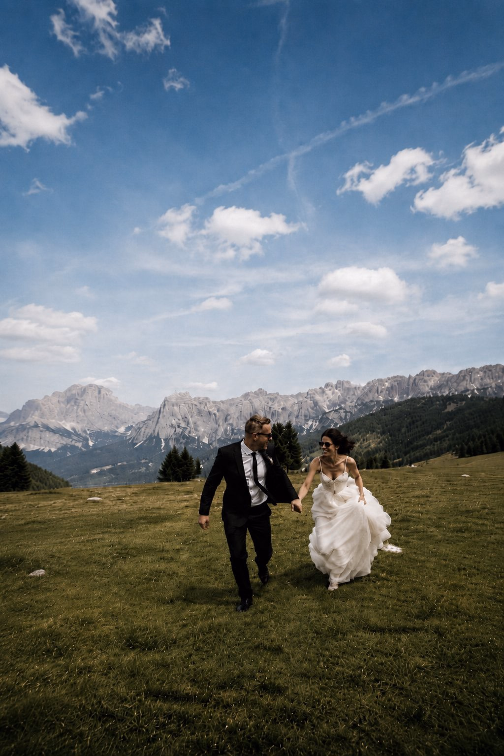 Newlyweds walking together through a mountain meadow