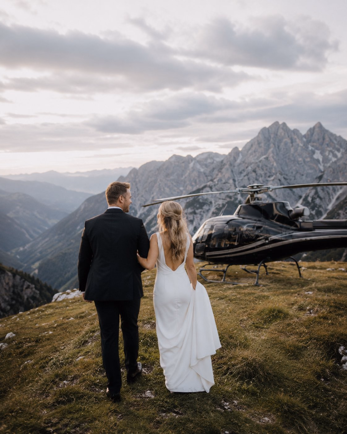 Newlyweds walking towards a helicopter in the mountains