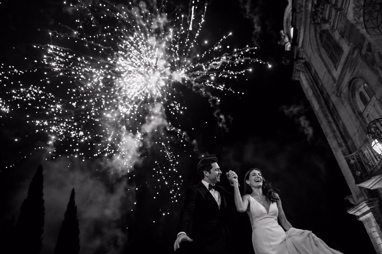Bride and groom watching fireworks outside a historic building