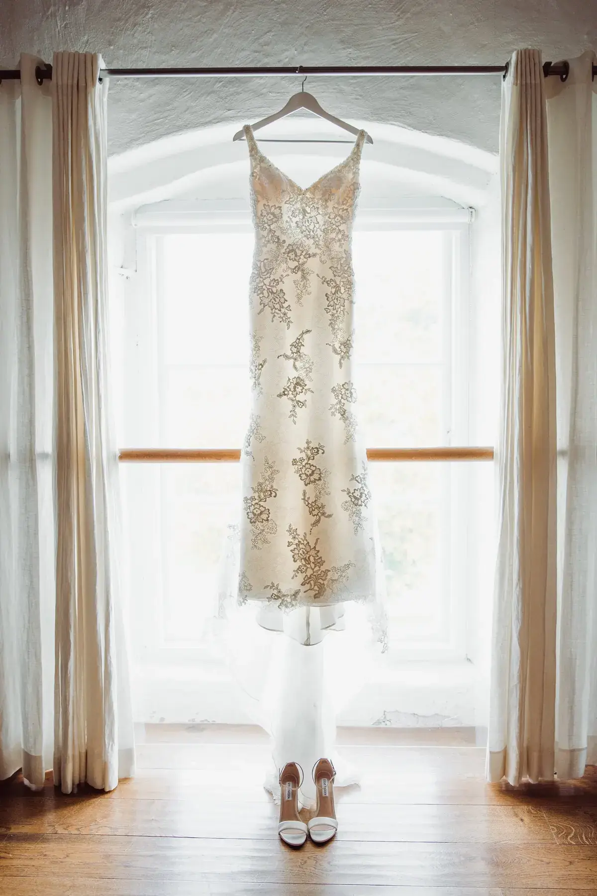 A wedding dress photographed beside a window.