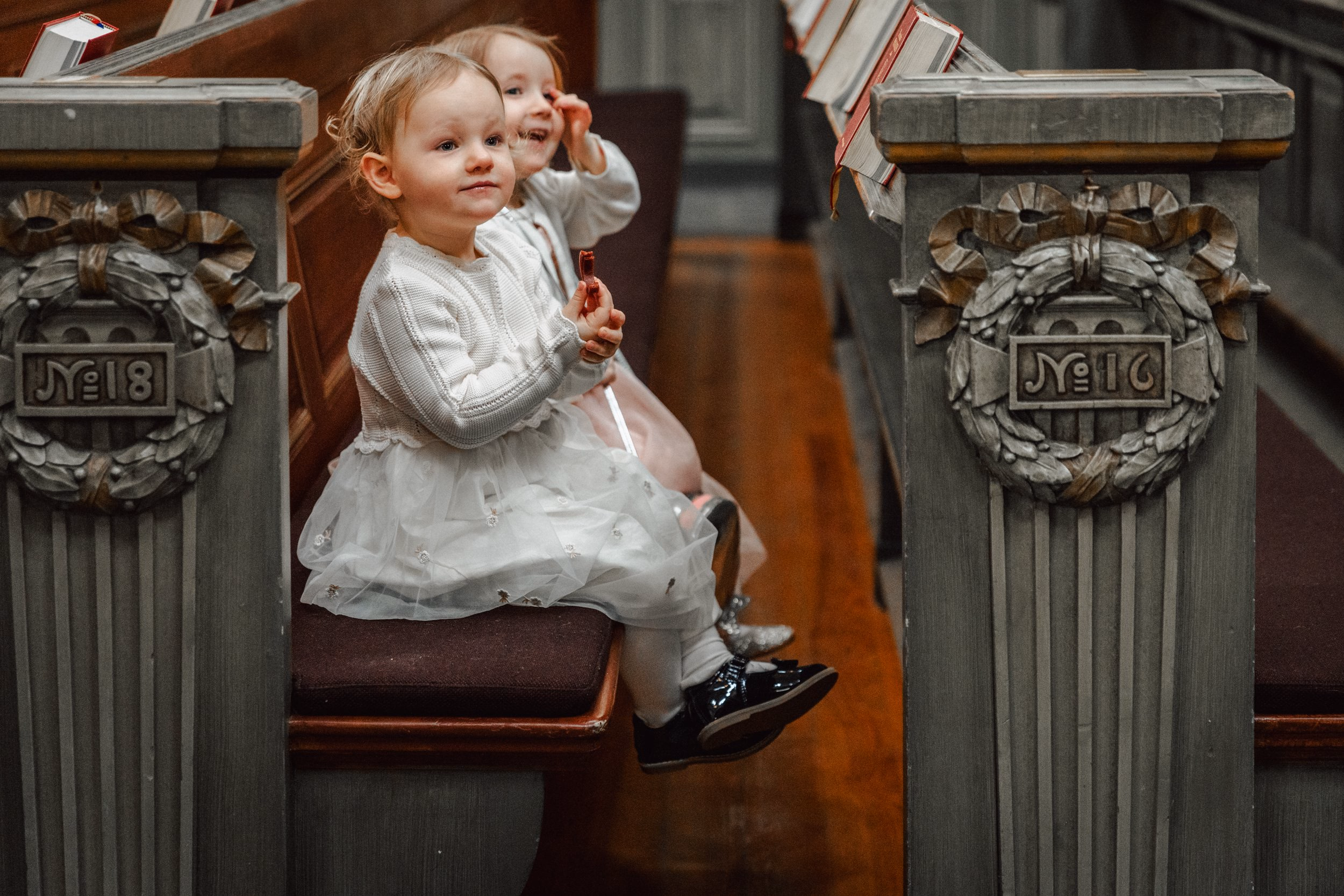 Young child sitting between carved wooden church pews