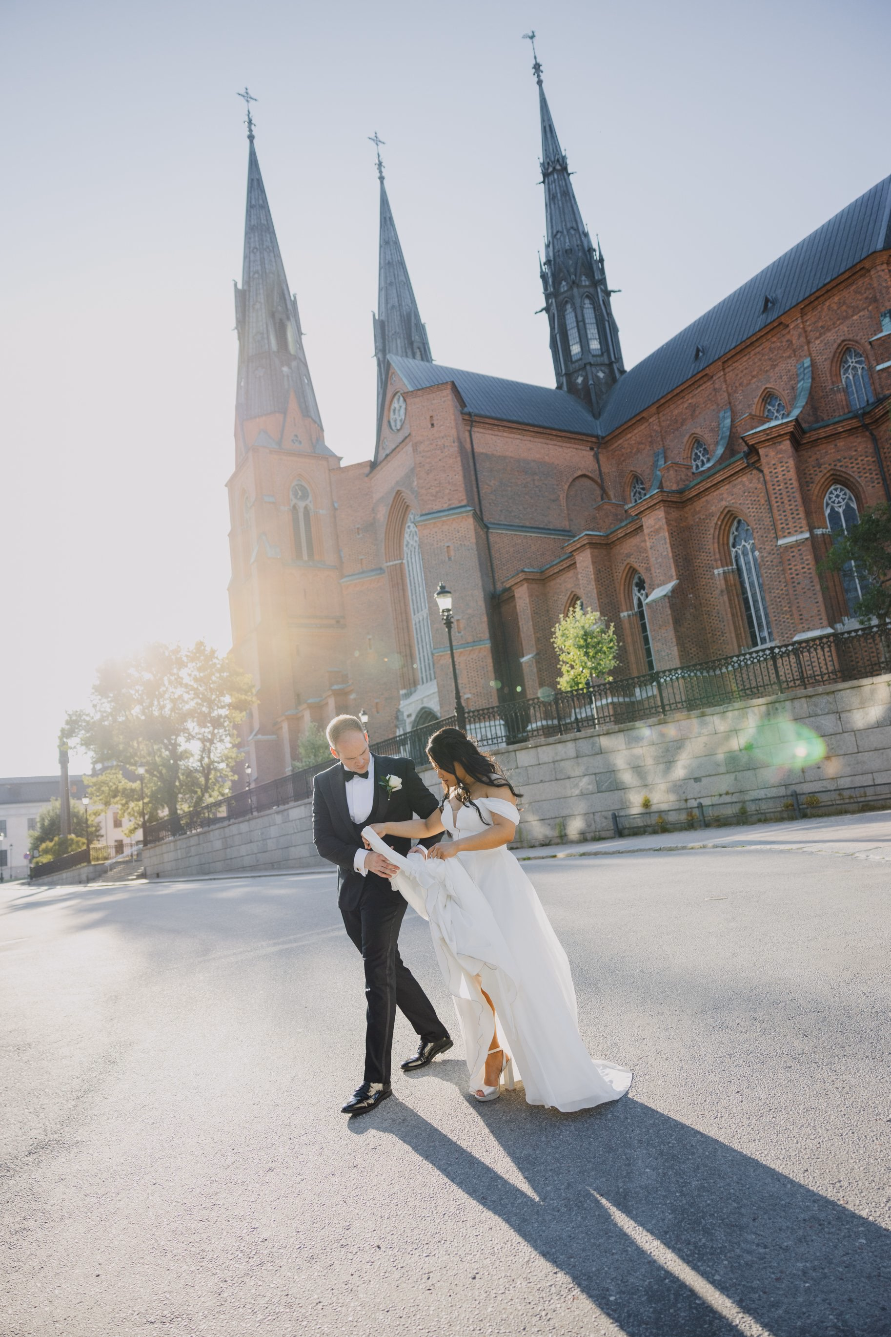 Newlyweds crossing a sunlit square outside a church