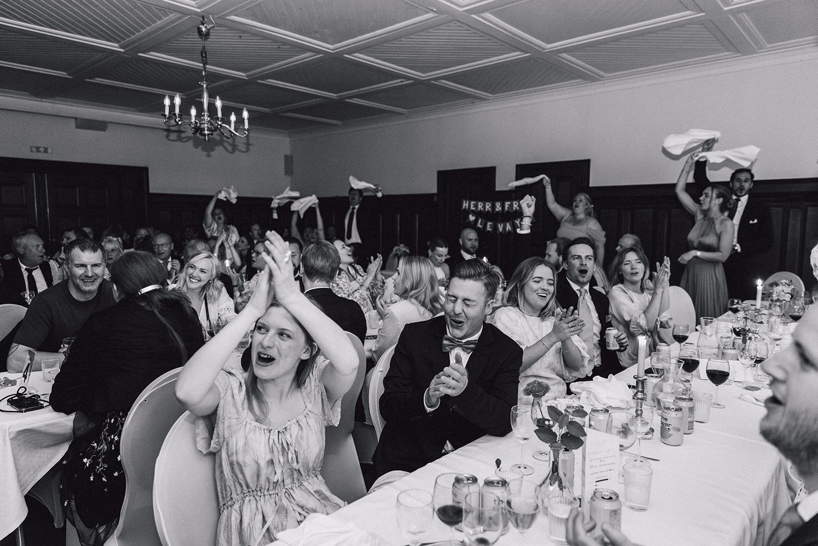 Wedding guests celebrating with raised napkins in black and white