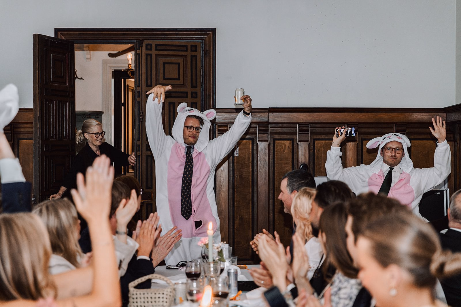 Wedding guests applauding two people in chef hats during dinner