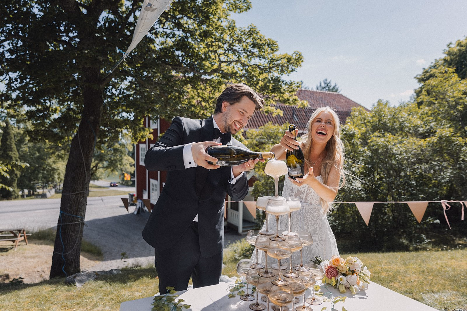 Newlyweds laughing while cutting their wedding cake outdoors