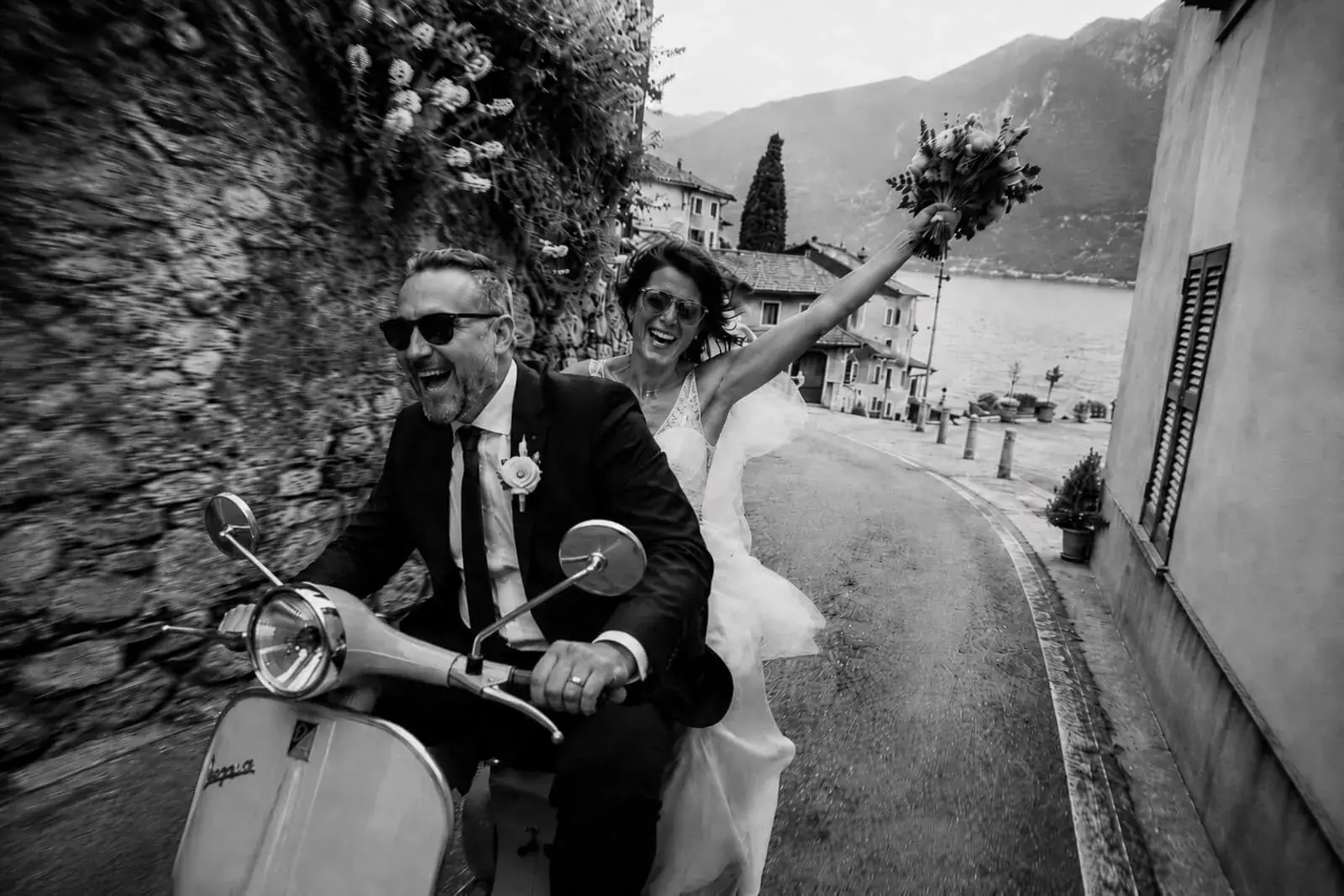 Newlyweds riding a Vespa beside a lake in Northern Italy.