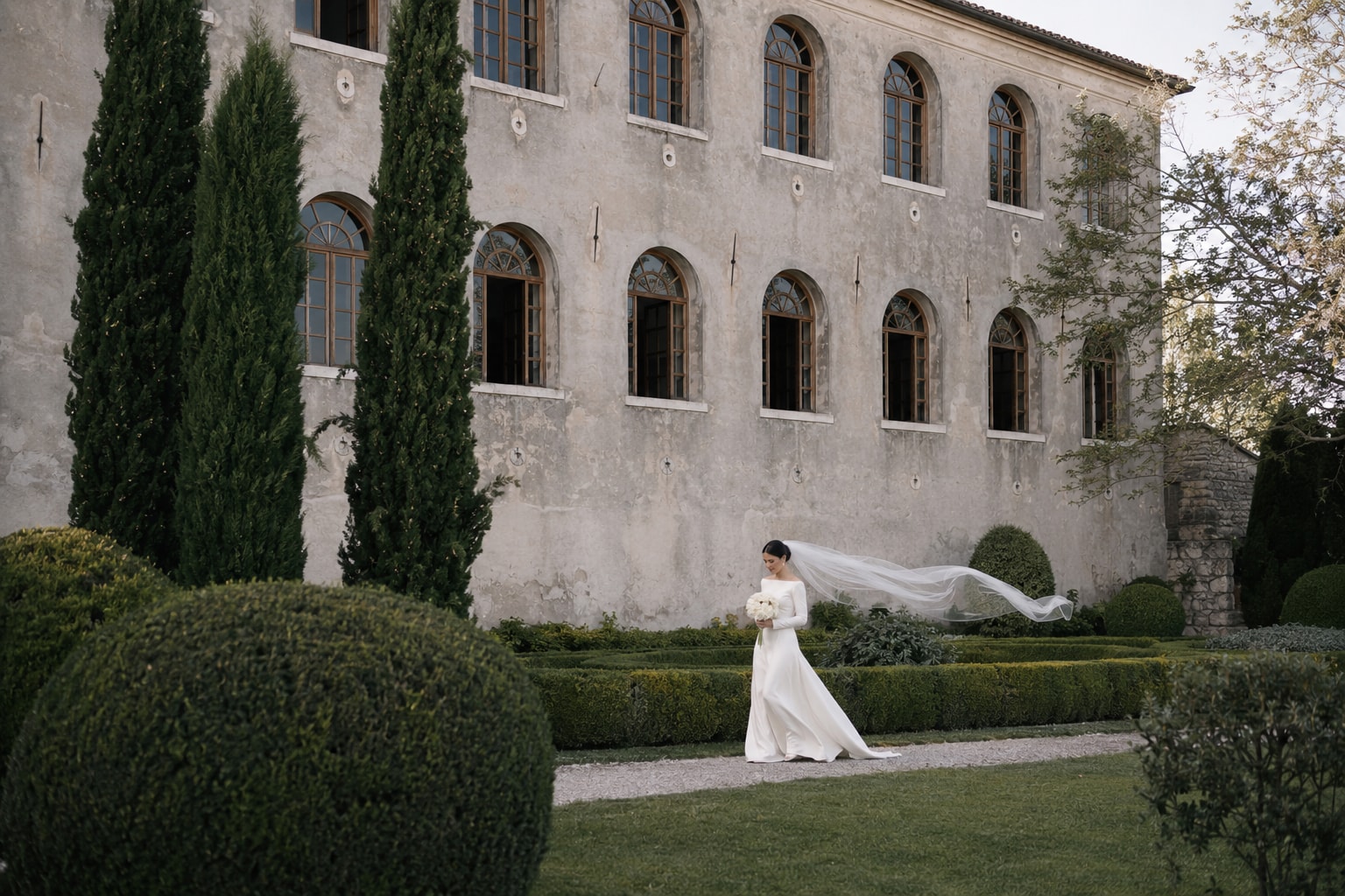 Bride walking through the historic gardens of Villa San Vigilio on Lake Garda, Italy, during elegant wedding portraits.