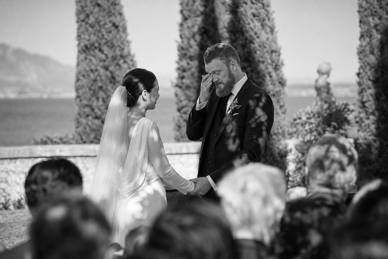 Emotional wedding ceremony at Villa San Vigilio, Lake Garda, Italy, with bride and groom exchanging vows overlooking the lake.