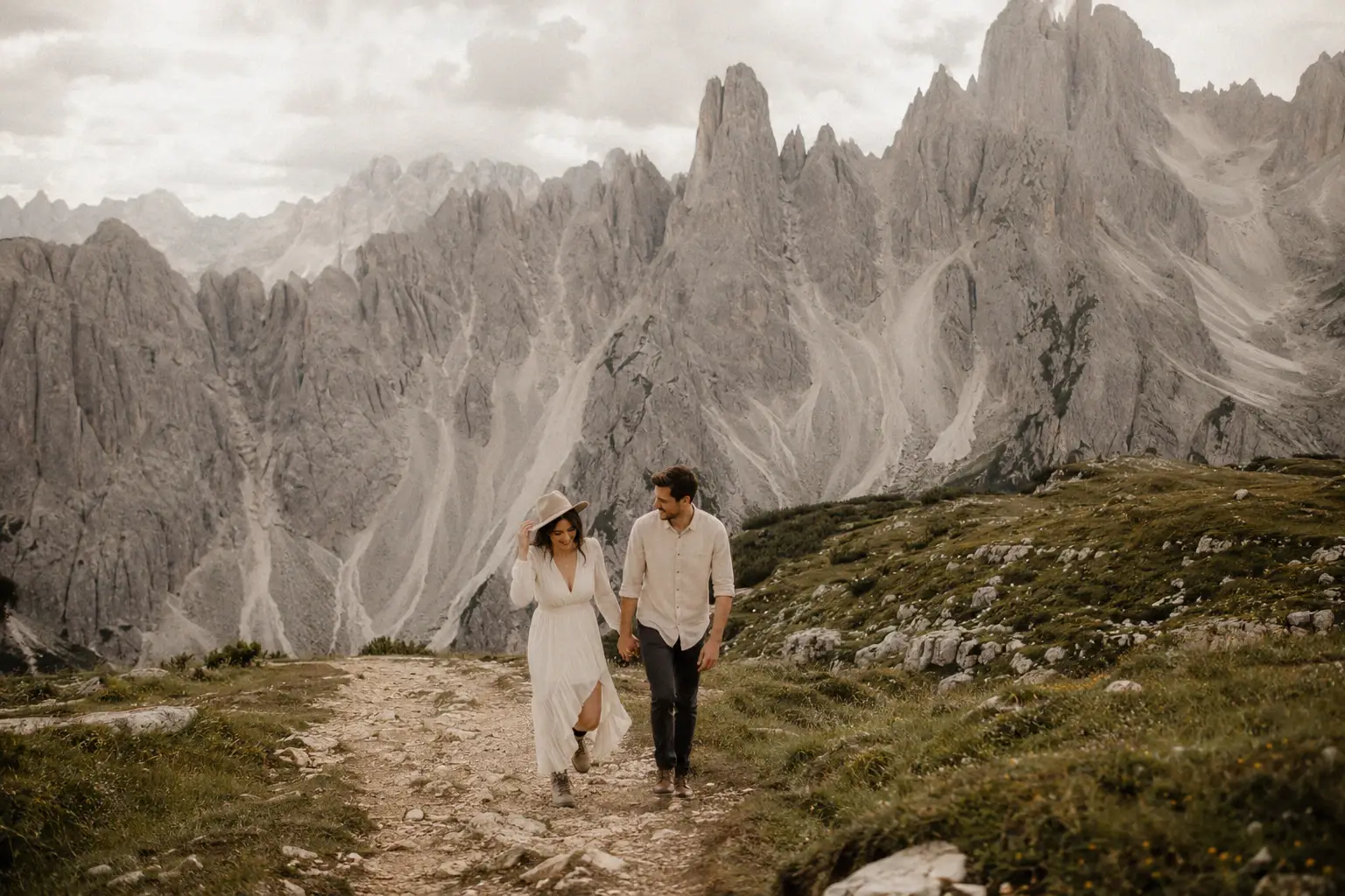 Bride and groom embracing beside Lago di Carezza in the Italian Dolomites during golden hour, with emerald alpine water.