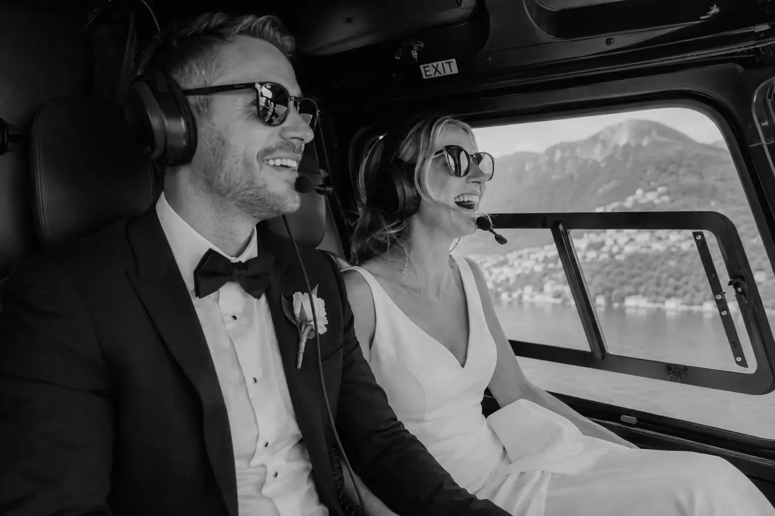 Newlyweds laughing together inside a helicopter.