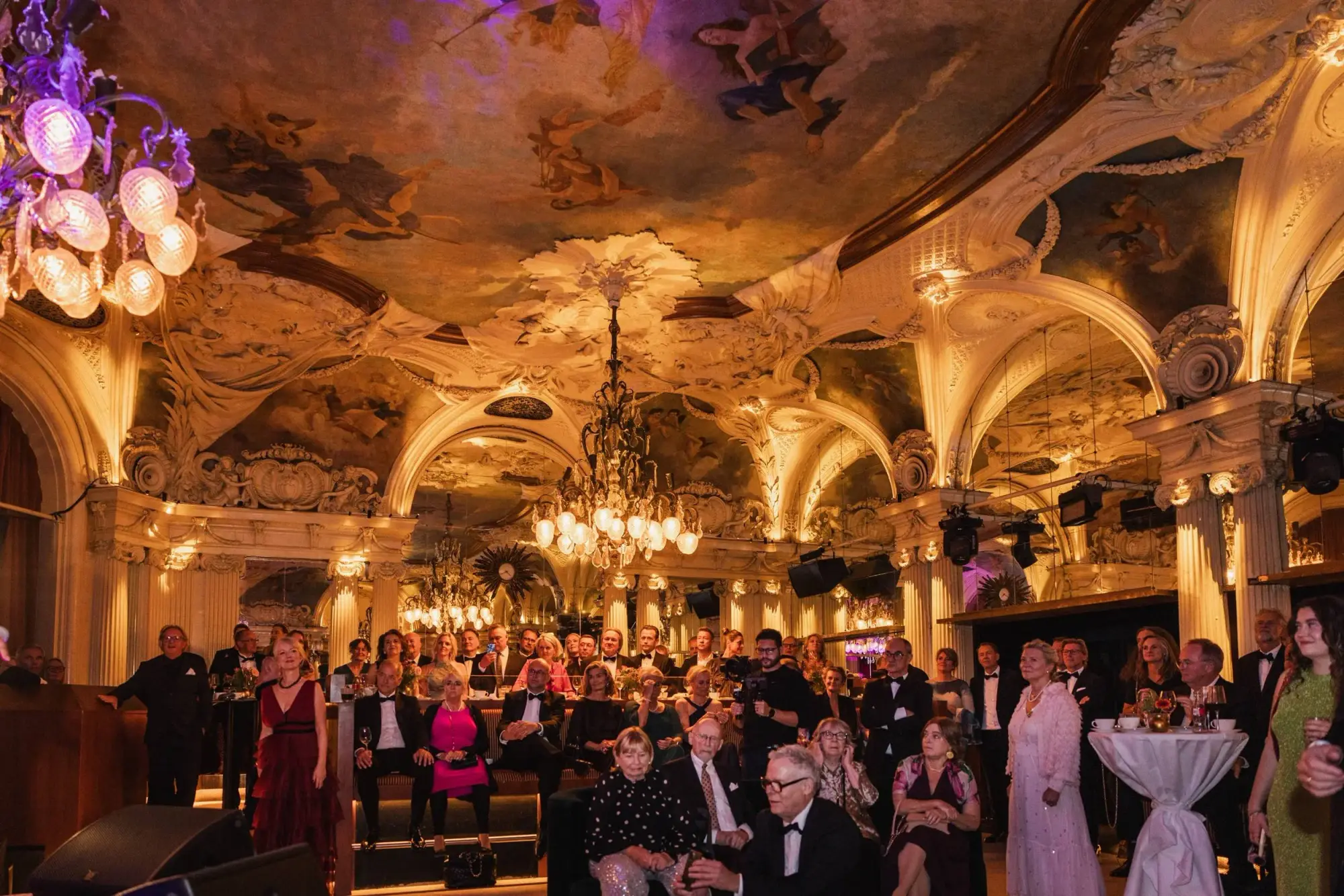 International wedding guests gathered beneath the chandeliers and painted ceiling of Café Opera