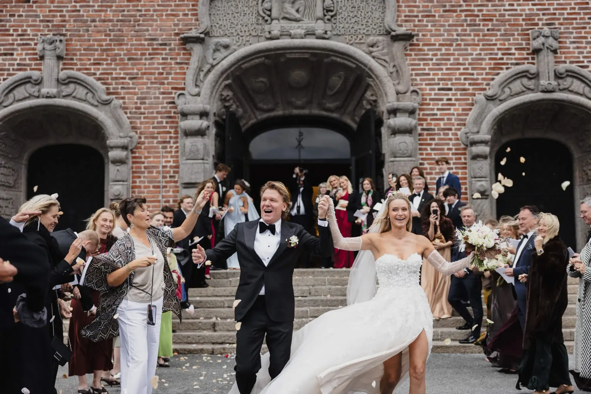 Newlyweds celebrating outside a Stockholm church as guests throw rose petals.