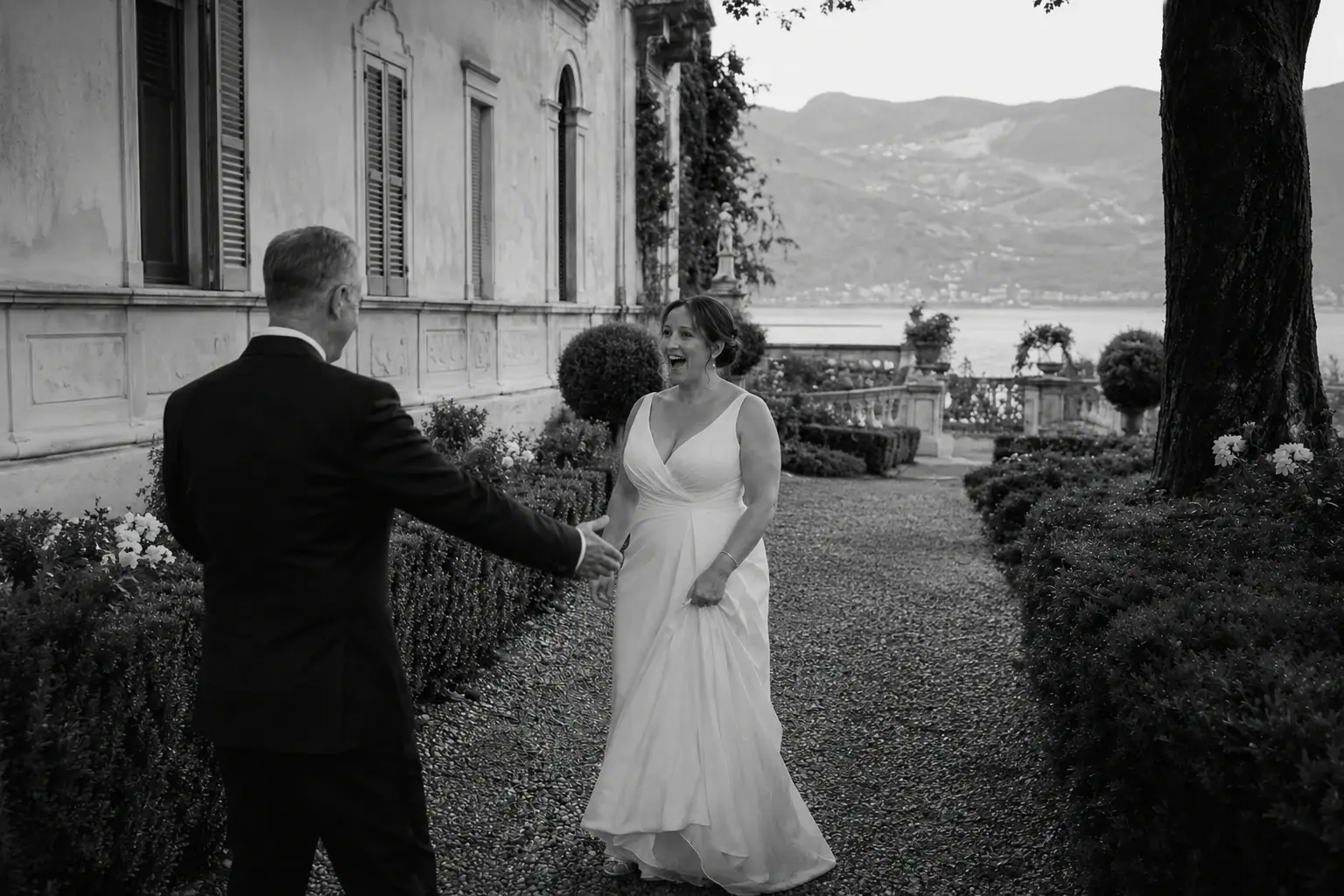 Bride and groom during a first look in the gardens of Villa Pizzo with Lake Como and mountains in the background.