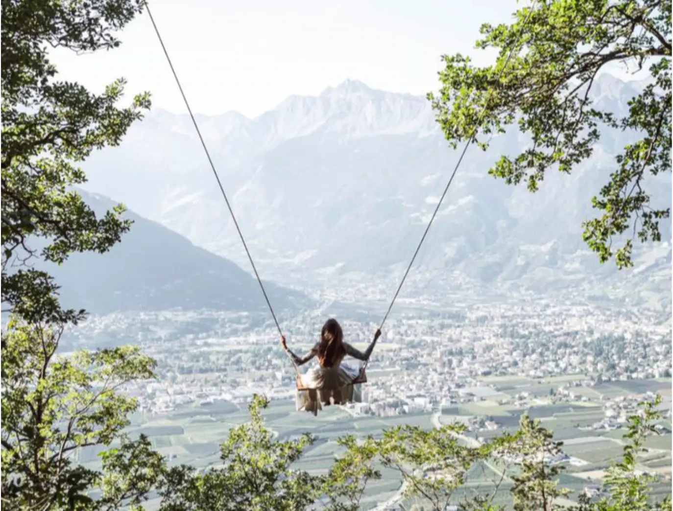 Person on a swing overlooking a mountain valley.