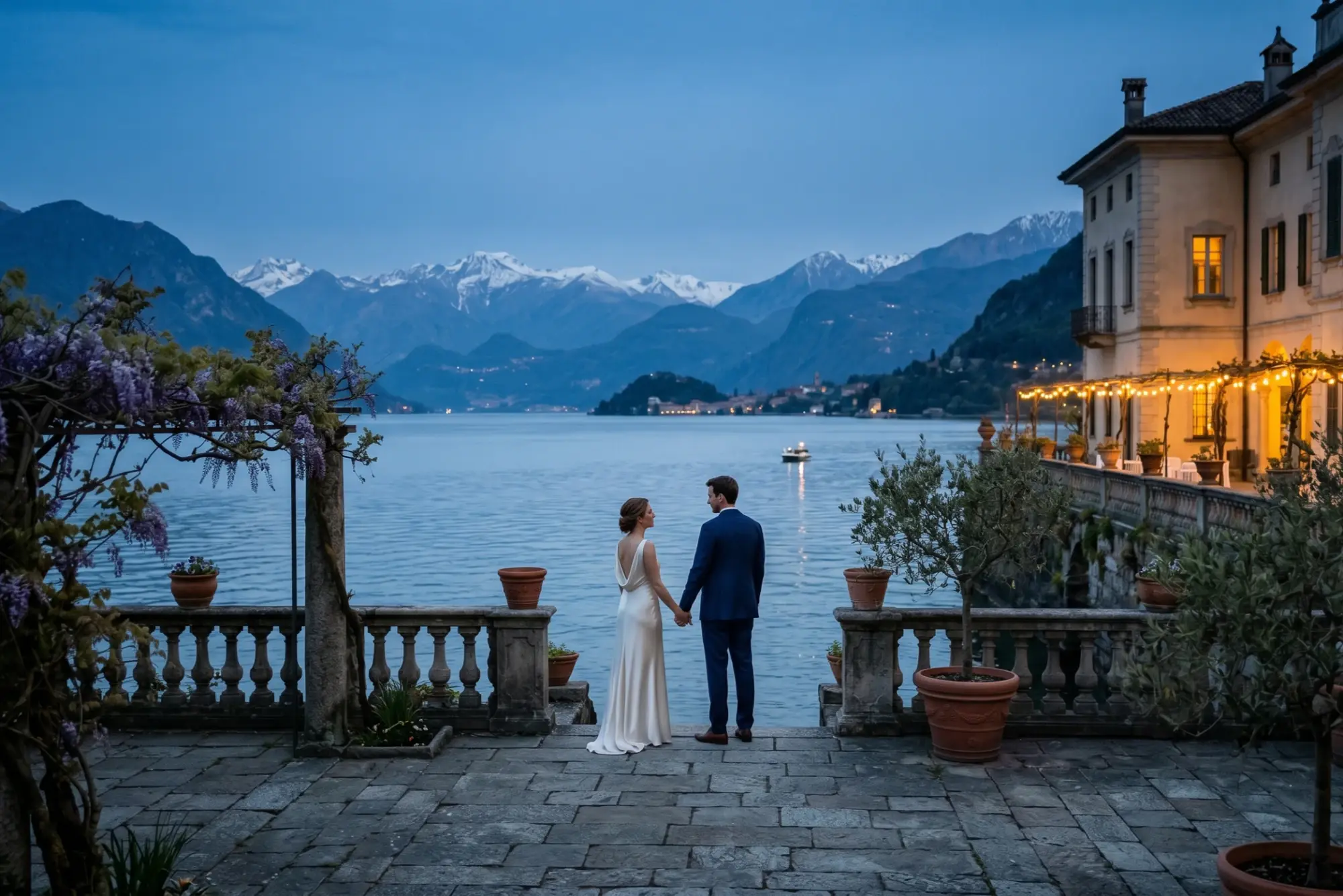 Couple standing on a terrace overlooking a lake and mountains.