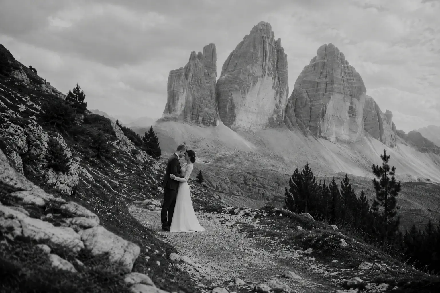 Couple standing on a mountain ridge beneath the Tre Cime peaks.
