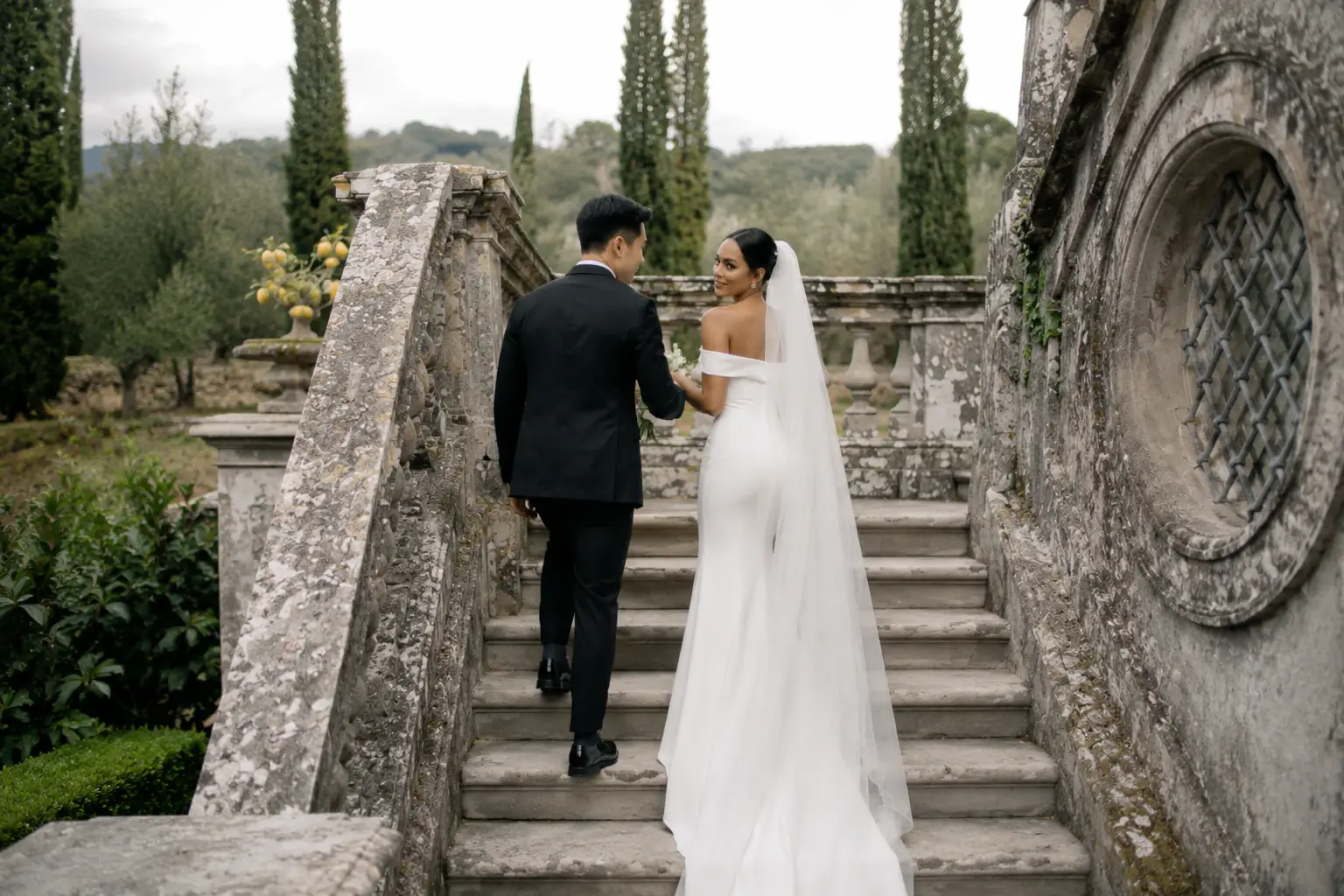 Bride and groom walking up the historic stone staircase at Villa Cetinale during a destination wedding in Tuscany.