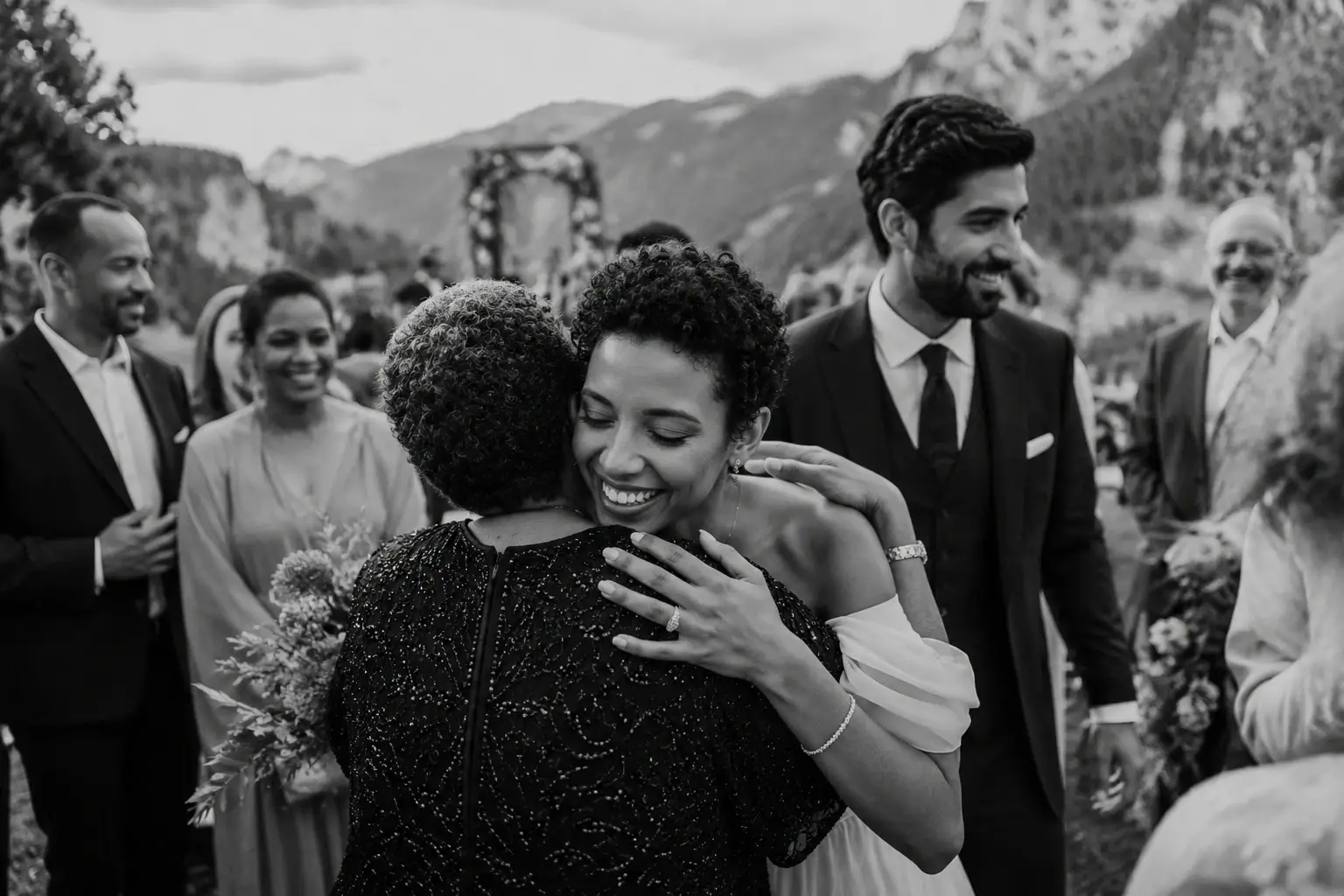 Bride hugging a wedding guest after an intimate ceremony in the Dolomites with family and friends celebrating nearby.