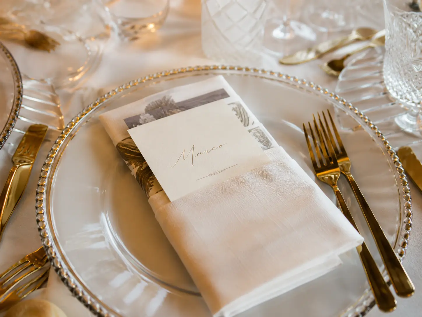 Elegant wedding dinner table detail at Grand Hotel Tremezzo with personalized place setting, gold cutlery and candlelit reception atmosphere.