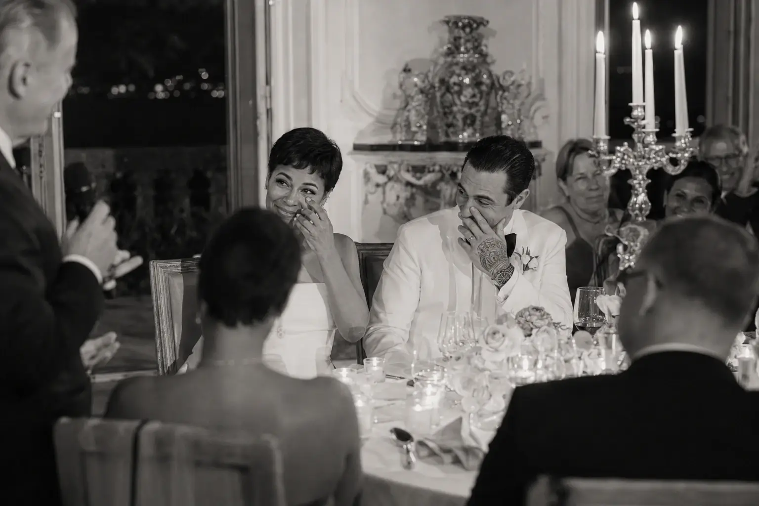 Emotional black and white dinner speech moment at Villa Sola Cabiati with couple laughing during candlelit reception on Lake Como