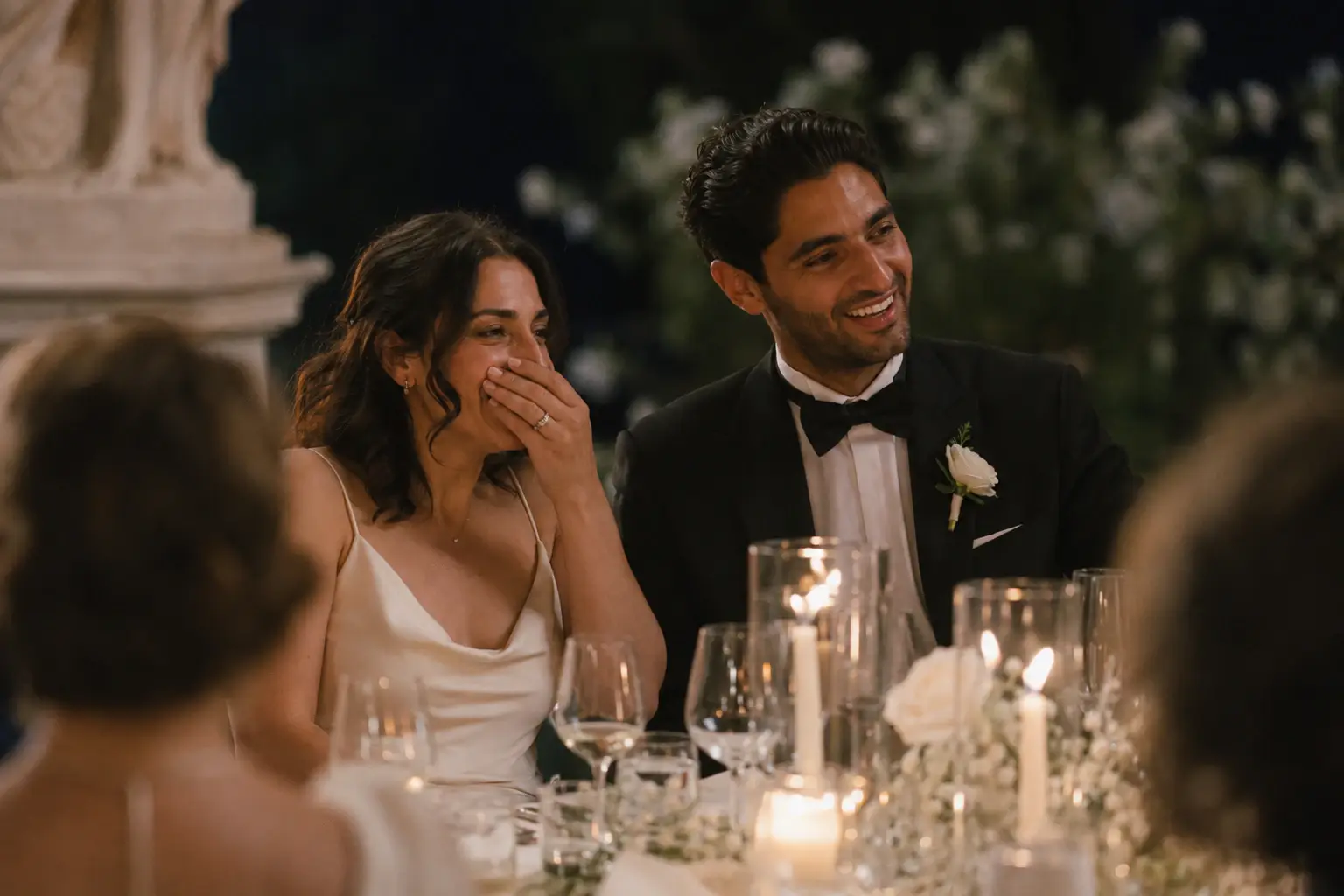 Newlyweds laughing together at their wedding dinner.