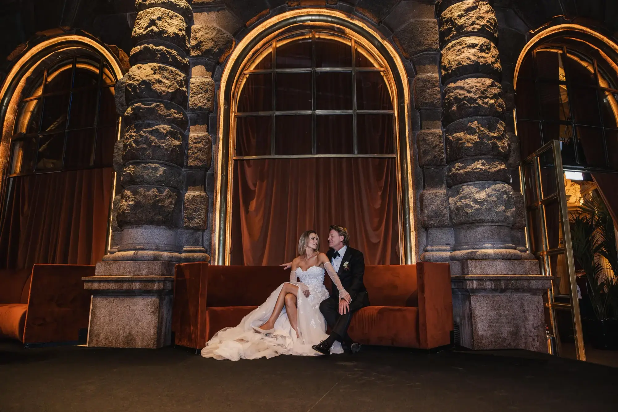 Full-length wedding portrait of a couple beneath a chandelier at Café Opera Stockholm