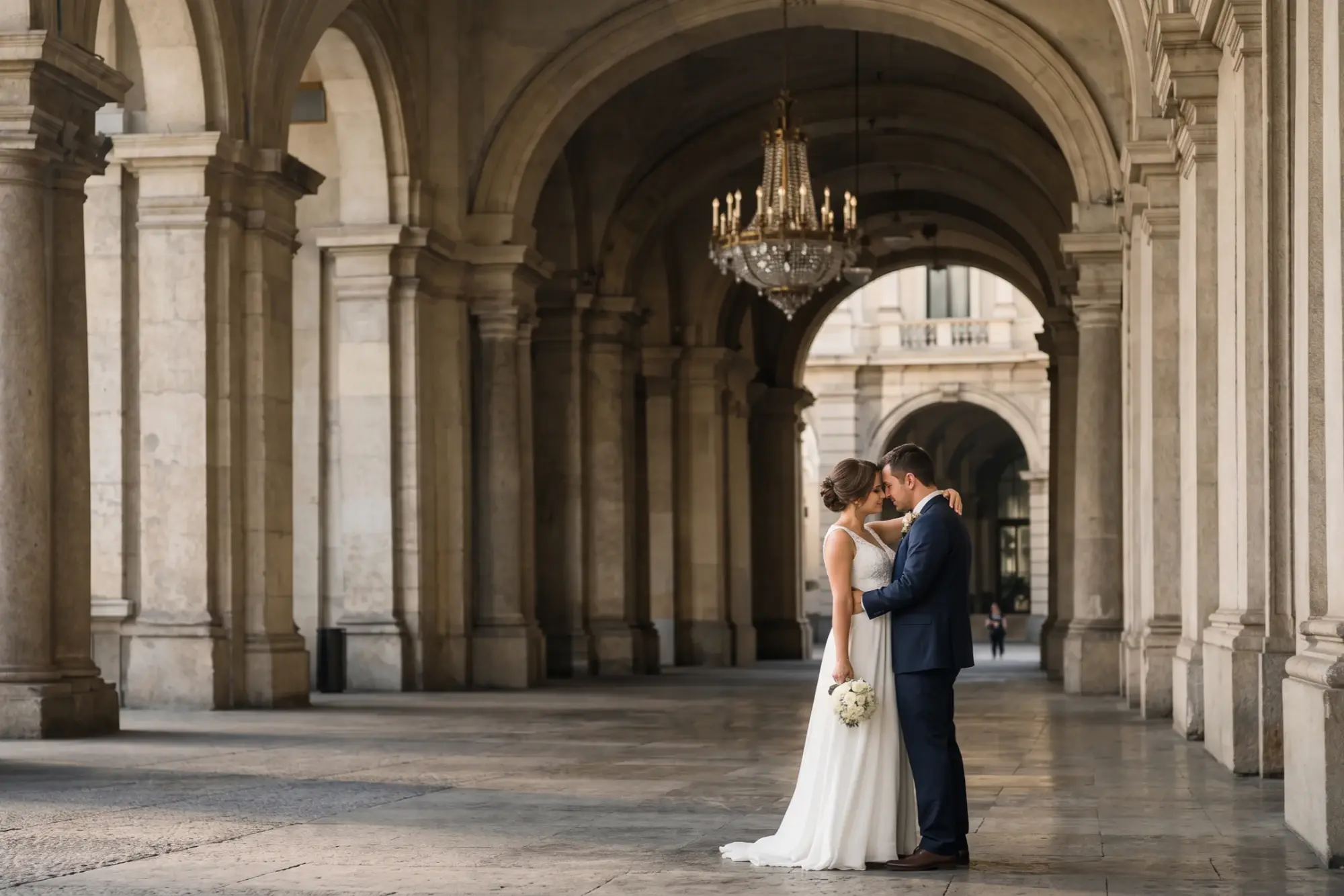 Couple kissing beneath an arched stone colonnade.