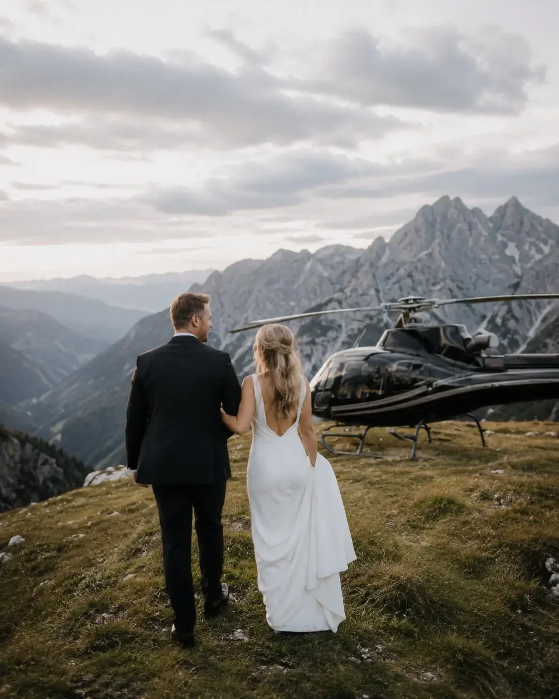 Couple looking toward a helicopter on a mountain ridge.