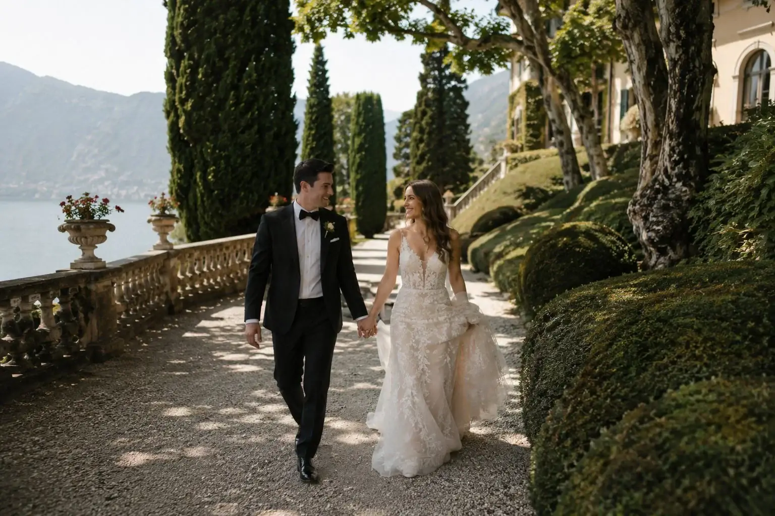 Bride and groom walking through the gardens of Villa del Balbianello in Lenno, Lake Como, surrounded by cypress trees and cinematic lake views.