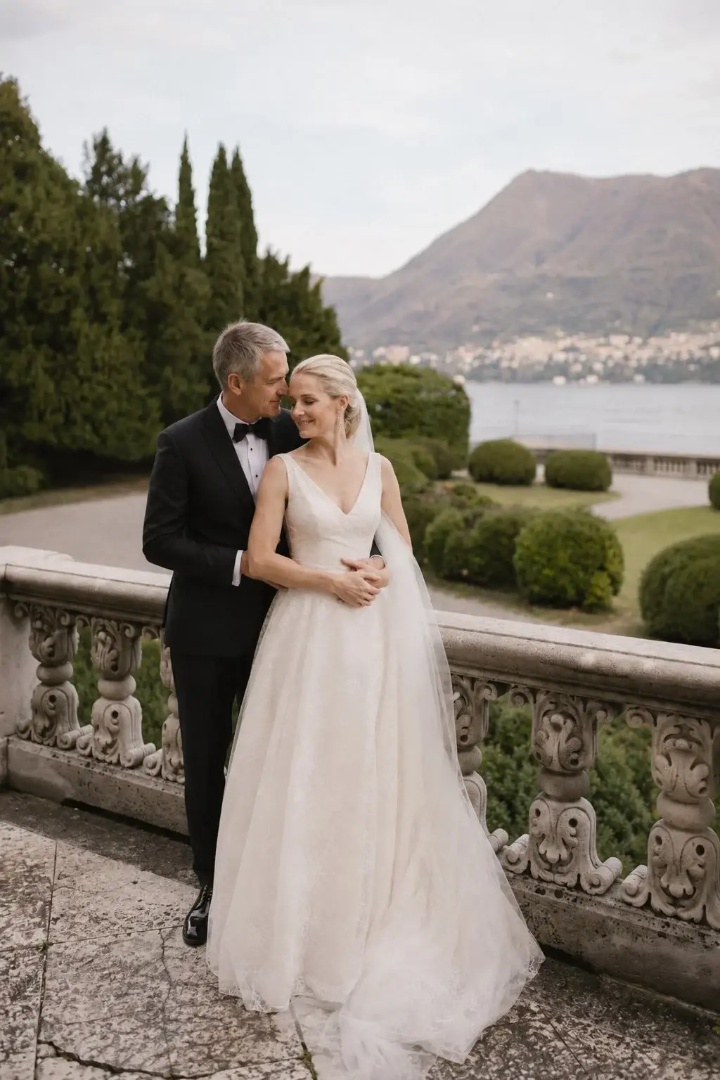 Newlyweds embracing on a terrace overlooking Lake Como.