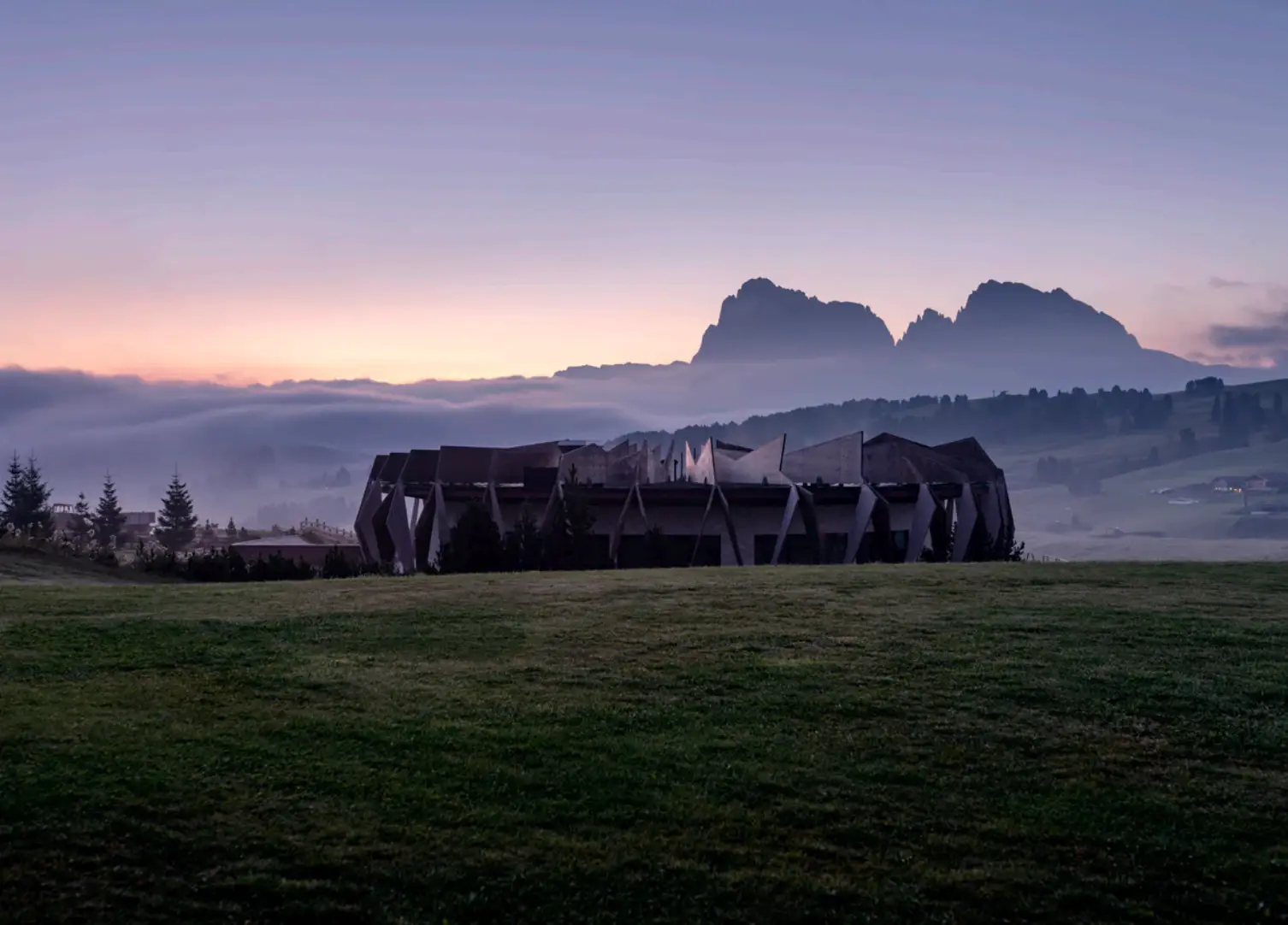 Low mountain lodge in a meadow at sunset.