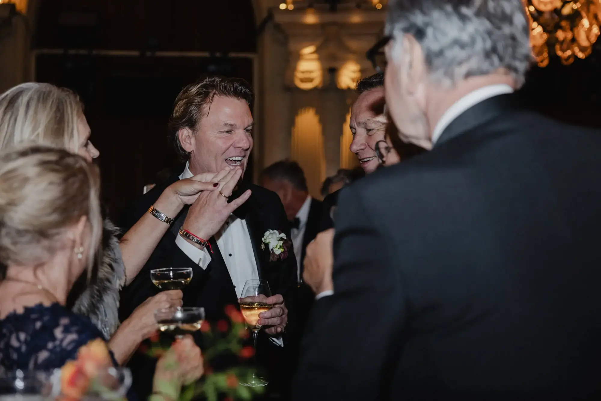 Groom laughing with friends during an international wedding reception at Café Opera