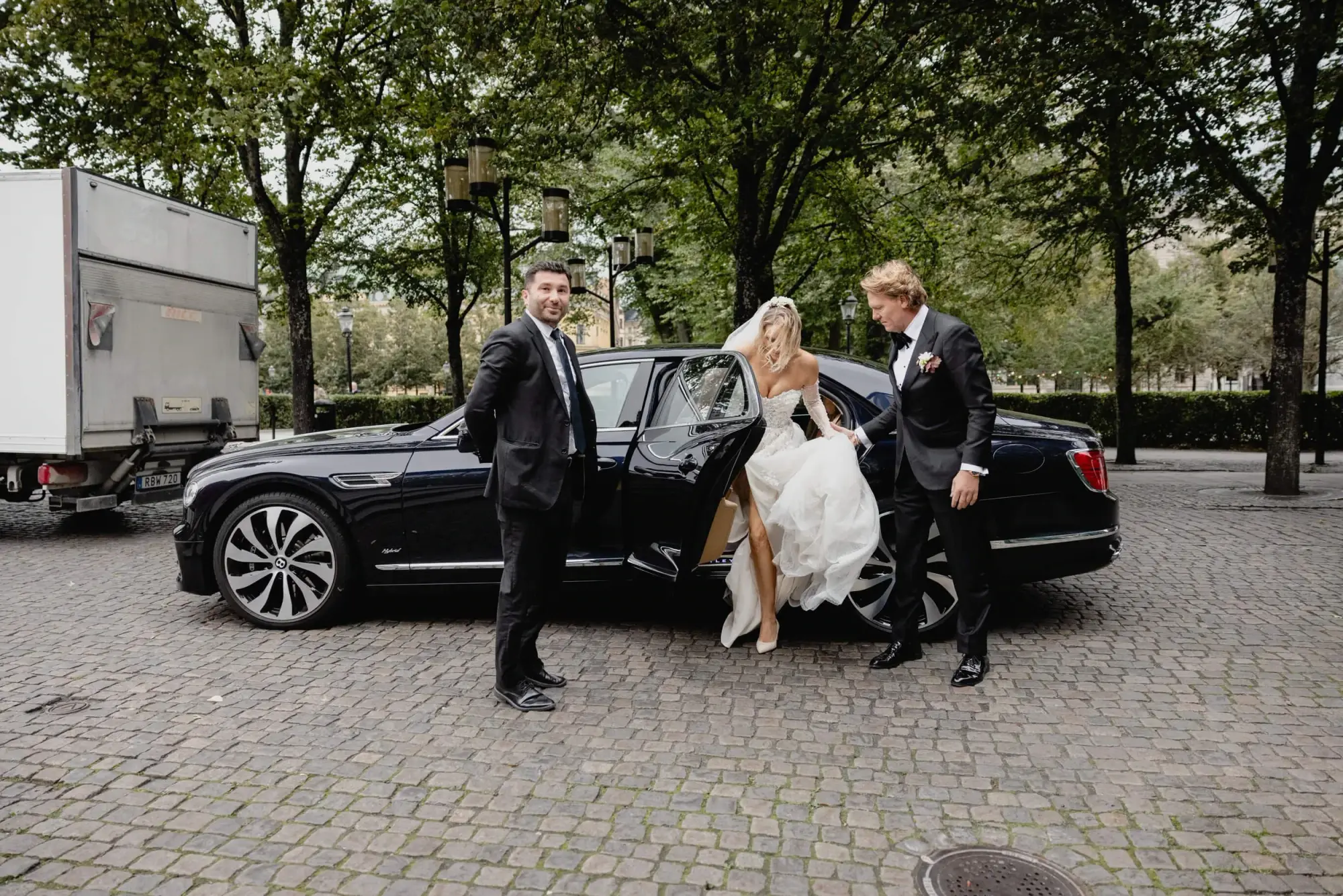 Bride stepping from a chauffeur-driven car with the groom as they arrive at Café Opera