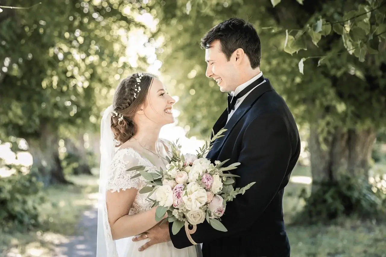 Bride and groom smiling at each other in a garden.