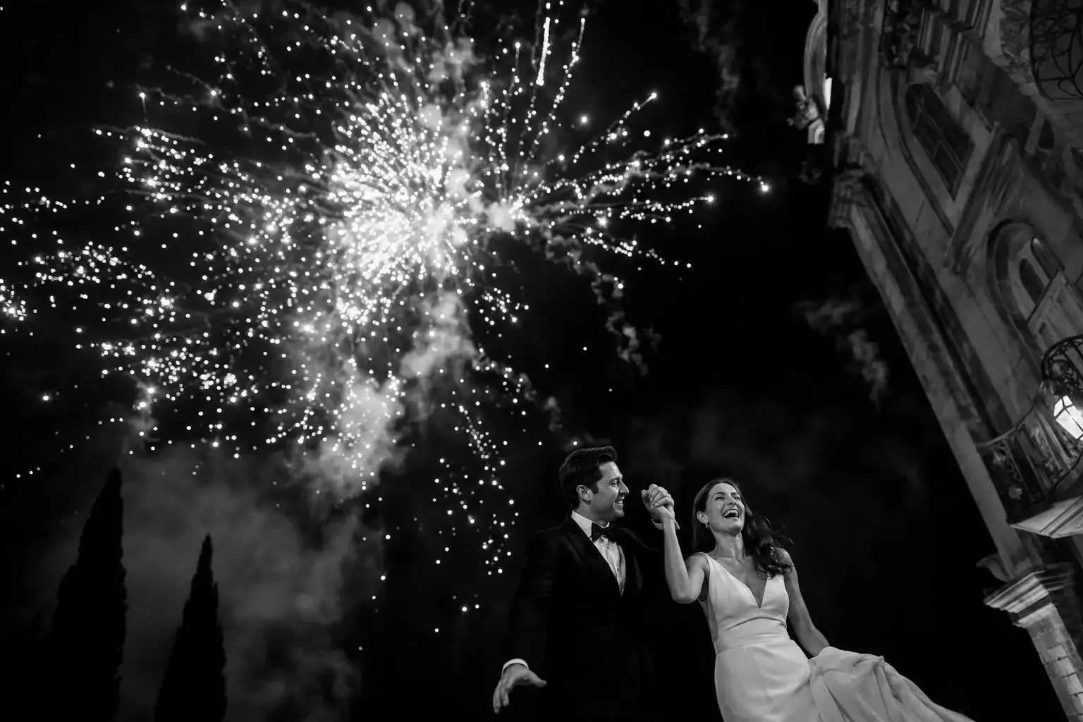 Newlyweds celebrating beneath fireworks outside a church.