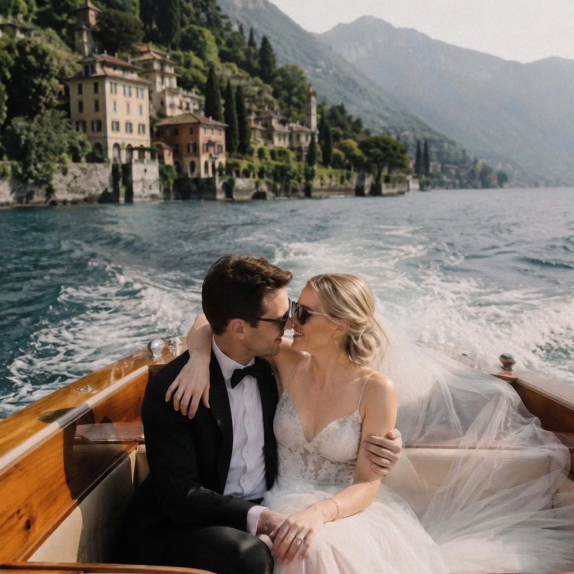 Bride and groom embracing on a classic wooden boat during a Lake Como wedding.
