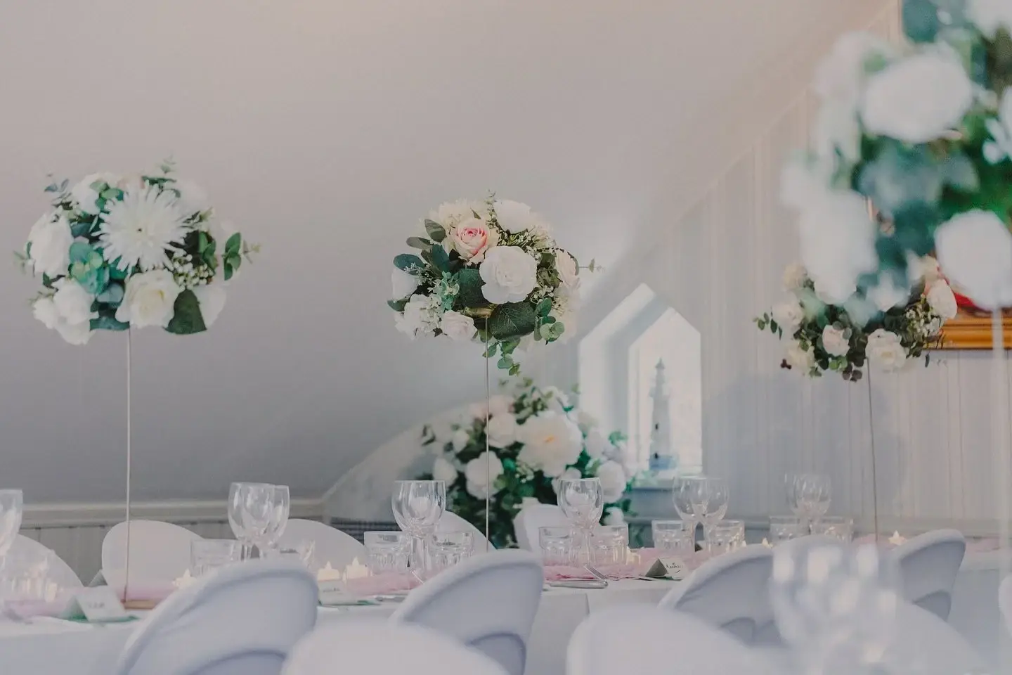 Wedding reception table decorated with flowers and glassware.