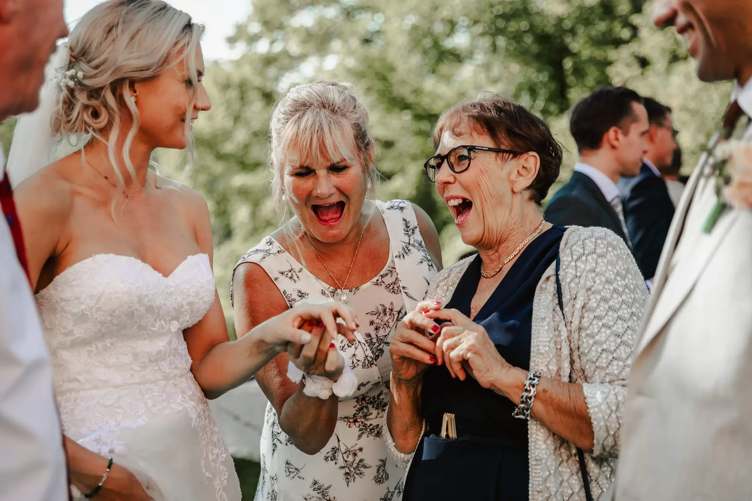 Group of people celebrating outdoors, engaging in conversation and laughter, at a wedding event.