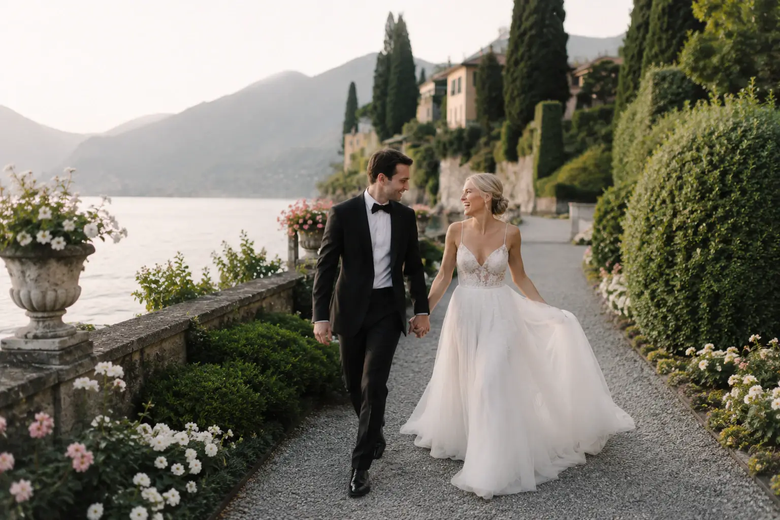 Newlyweds walking along a lakeside terrace.